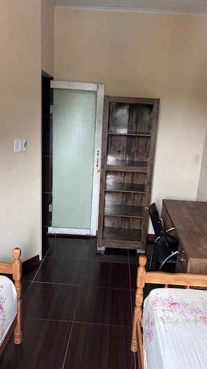 A room with a bed, a wooden wardrobe, a desk, and a door leading to another room. - Townhouse with pool and air conditioning near Caraguatatuba shopping mall (Caraguatatuba)