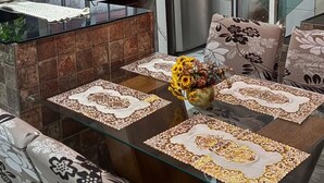 Une cuisine moderne avec une table à manger en verre, des coussins à motifs et des luminaires suspendus.