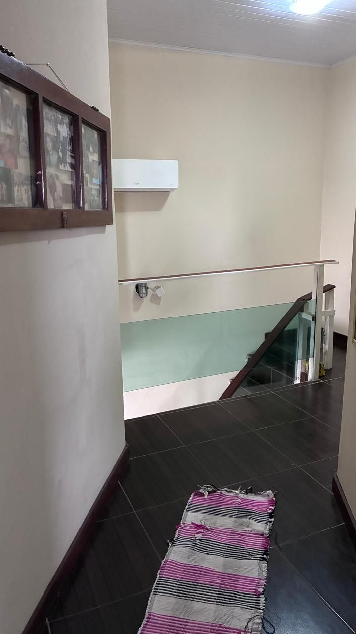 A staircase with a glass railing, a dark floor, and a patterned rug.