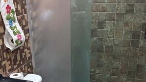 Une salle de bain comprenant des toilettes, un bidet, un espace douche et un mur carrelé.