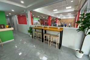 A reception area with a counter, seating, and a potted plant. - Chill Chill Hotel (Krabi)
