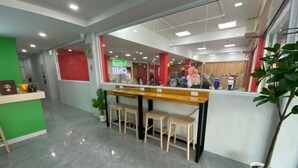 A reception area with a counter, three stools, and a potted plant.