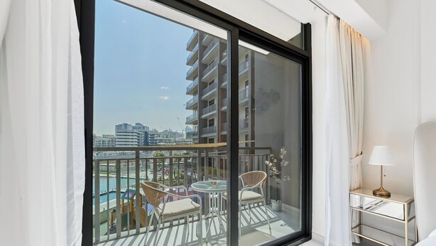 Un balcone con vista sulla città, un tavolo con sedie e una lampada su un comodino.