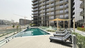 Area piscina sul tetto con poltrone relax, una piscina e vista su un grattacielo.