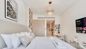 Una camera d'albergo moderna con un letto grande, un'area pranzo e una cucina sullo sfondo.