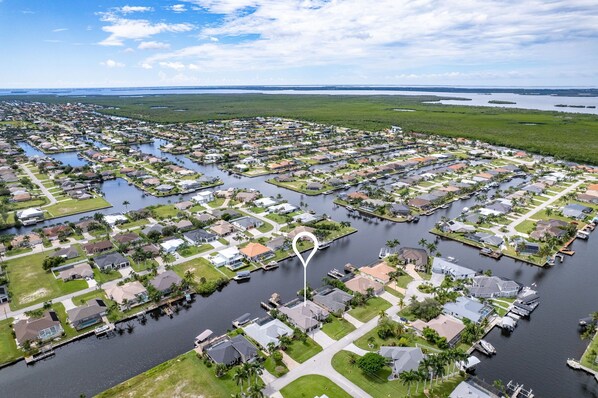 An aerial view of a residential area with houses arranged around water bodies, likely a lake or river.