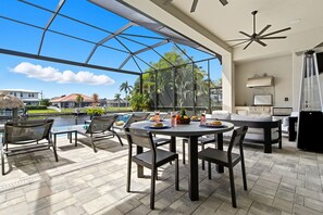 A spacious outdoor patio with a glass enclosure, a round dining table, and modern outdoor furniture.