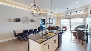 Une cuisine moderne dotée d’un îlot central, d’un coin bar et offrant une vue sur l’extérieur.