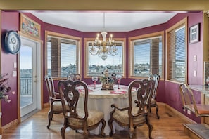 A dining room with a round table, ornate chairs, a chandelier, and large windows with blinds. - Mountain View Chateaux - A Lavish Mountain Retreat - Perfect for Large Families (Layton)
