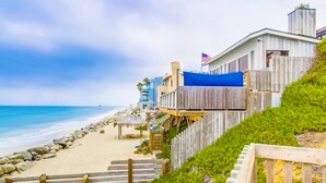 Una propiedad frente a la playa con una terraza de madera, una bandera y vista al océano.