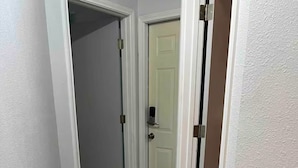 A narrow hallway with a wooden floor, a white door with a doorknob, and a brown doormat. - Hook, Relax & Stay: 3 BR Fishing Haven in Aransas Pass (Aransas Pass)