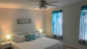 A bedroom with a bed, nightstands, a ceiling fan, and two windows with curtains. - Hook, Relax & Stay: 3 BR Fishing Haven in Aransas Pass (Aransas Pass)