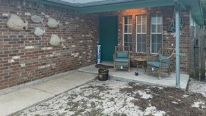 A brick building with a green door, two wicker chairs, and a small table. - Hook, Relax & Stay: 3 BR Fishing Haven in Aransas Pass (Aransas Pass)