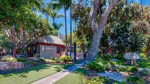 Un jardin bien entretenu, avec un chemin qui mène à un bâtiment portant l’inscription « North Coast Village ».