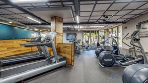 Une salle de sport équipée de tapis de course, de vélos elliptiques et de ballons d’exercice.