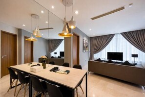 Una habitación de hotel moderna con zona de comedor, sofá y televisor.