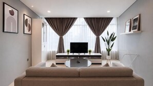 Een moderne woonkamer met een bank, televisie en gordijnen.