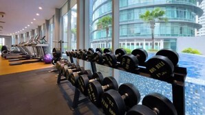 Een fitnessruimte met loopbanden, gewichten en een zwembad.