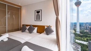 Een hotelkamer met een groot bed, uitzicht op de stad, een ingelijste afbeelding en een raam met gordijnen.