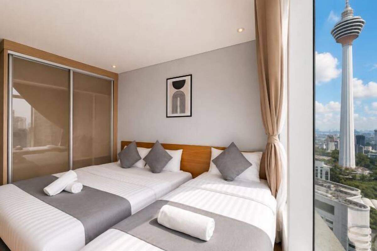 Une chambre d’hôtel avec deux lits, une grande fenêtre donnant sur la ville et une œuvre d’art encadrée accrochée au mur.