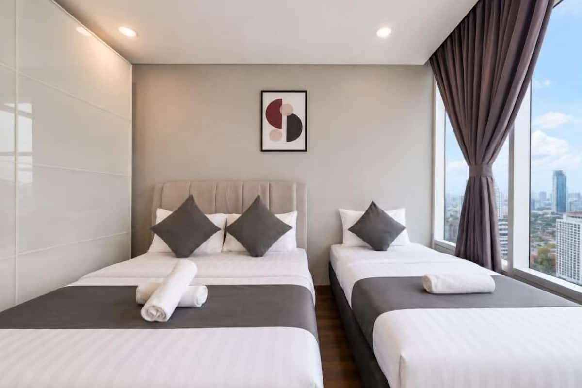 Une chambre d’hôtel avec deux lits, une vue sur la ville, une œuvre d’art encadrée au mur et une fenêtre avec des rideaux.
