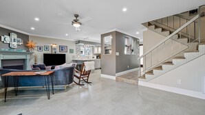 Un vaste salon doté d’une cheminée, d’un coin repas et d’un escalier menant à l’étage supérieur.