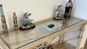 A glass-top table with metal legs, a framed picture on the wall, and decorative items on the table.