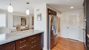 Una cocina moderna con refrigerador de acero inoxidable, armarios de madera y encimera de granito.