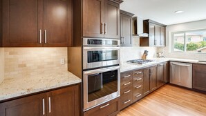Una cocina moderna con alacenas de madera oscura, electrodomésticos de acero inoxidable y un ventanal que proporciona luz natural.