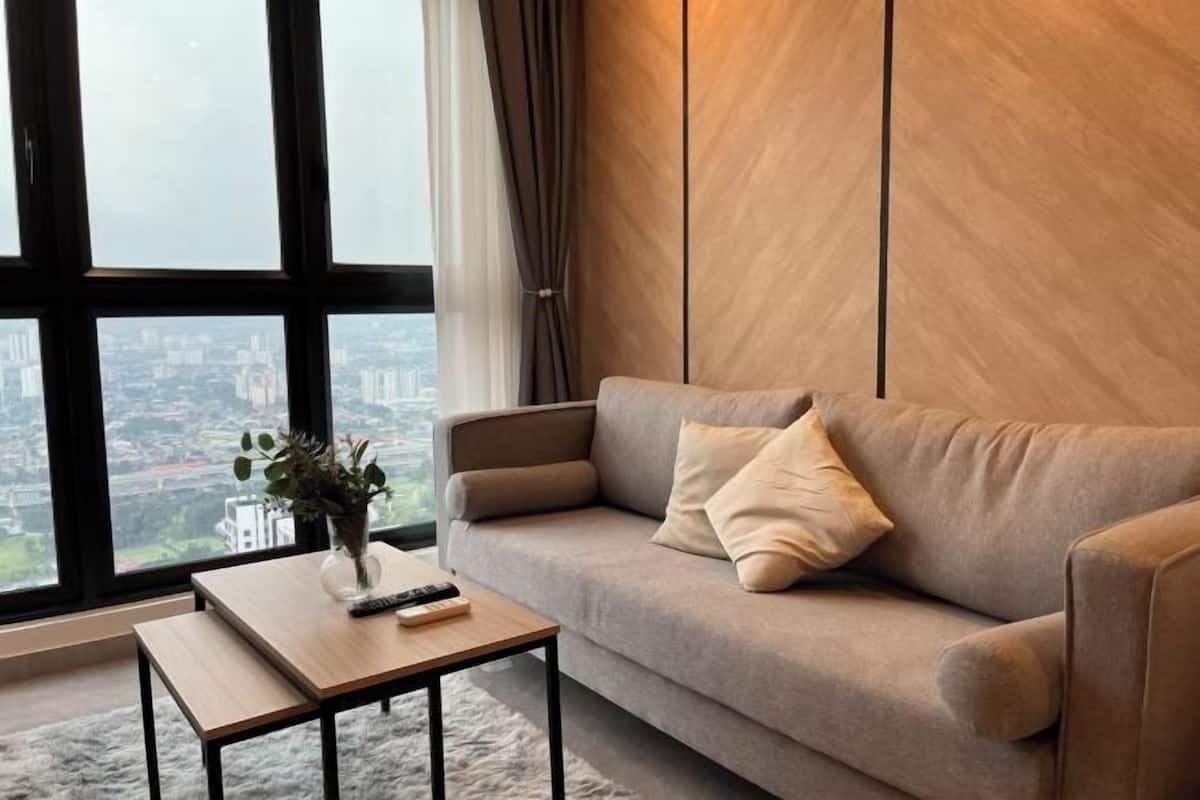 Ein modernes Wohnzimmer mit einer Couch, einem Couchtisch und Blick auf eine Stadtlandschaft durch große Fenster.