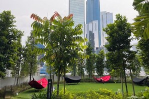 A landscaped area with trees and a view of tall buildings in the background. - Agile Bukit Bintang Suites at TRX KL (Kuala Lumpur)