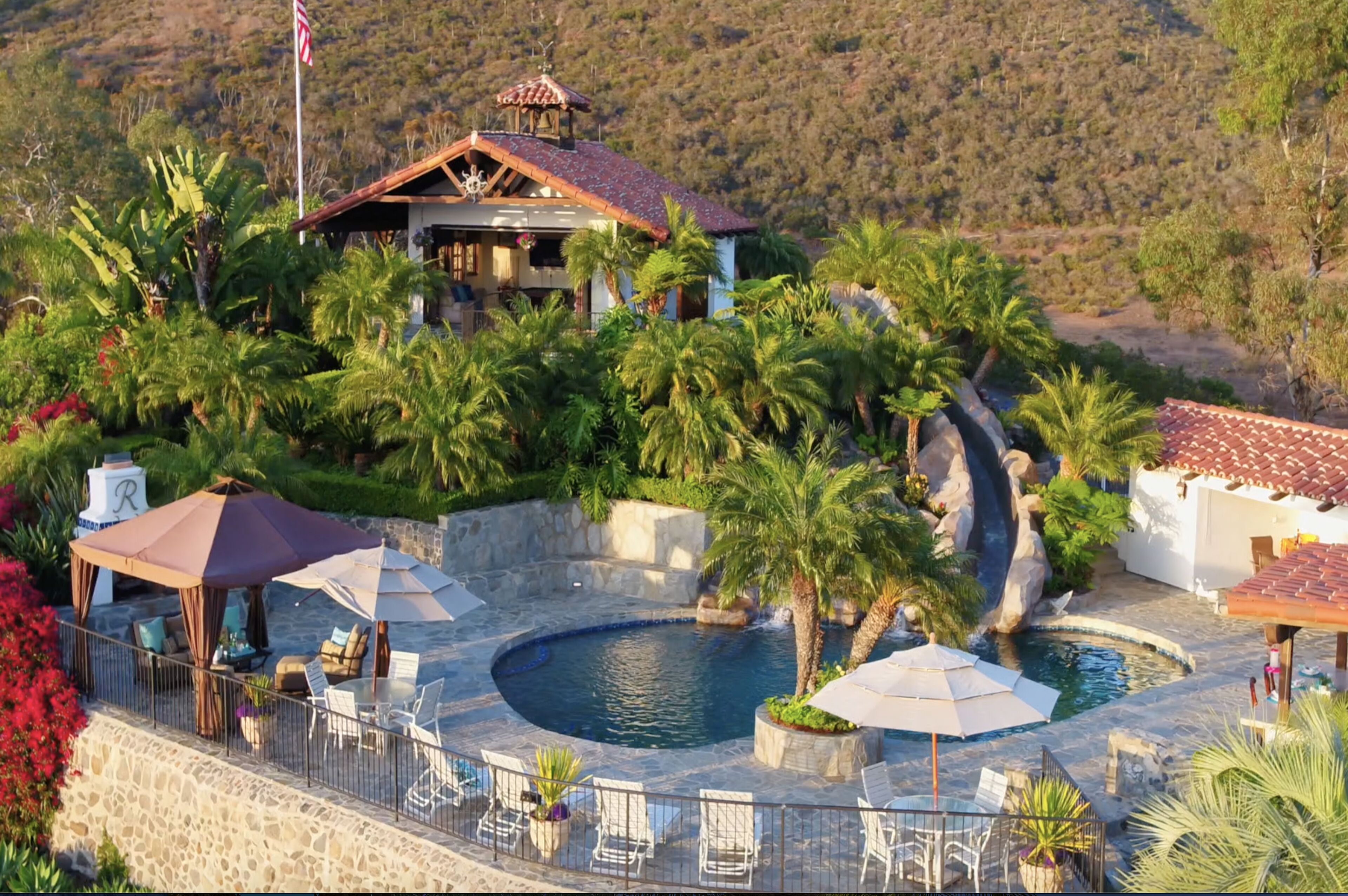 Un resort con piscina, area salotto esterna e vista sul paesaggio circostante.