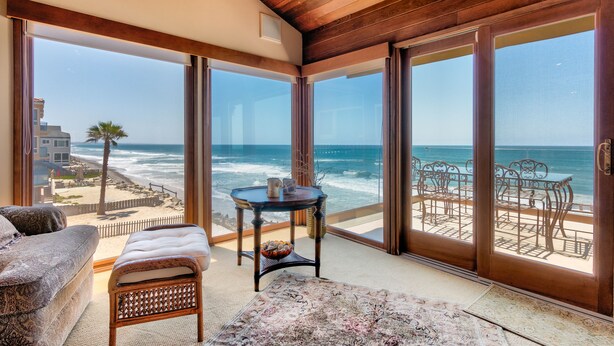 Ein Zimmer mit einer großen SchiebeglasTür, die auf einen Balkon mit Blick aufs Meer führt.