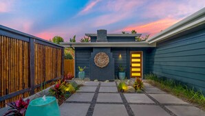 Una casa moderna amb façana fosca, una llar de pedra i un camí que condueix a l'entrada.