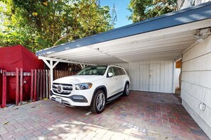 A white SUV parked in a covered garage with a brick floor.
