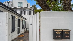 A narrow alleyway with a white building, a black and white striped awning, and a mailbox with the number 7258.