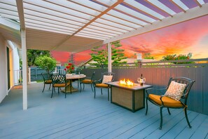 Eine Terrass mit Pergola, einem Tisch und Stühlen sowie einem Feuerkorb.