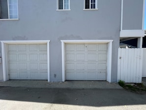A building with two garage doors and a white picket fence.