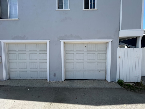 A building with two garage doors and a white picket fence.
