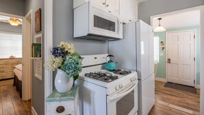 A kitchen with white cabinetry, a white stove, a white refrigerator, and a teal kettle on the stove.