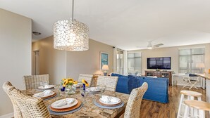 Un coin repas avec une table en marbre, des chaises en osier et un luminaire suspendu.