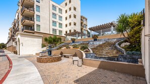 Une cour avec une fontaine, des sièges et un escalier menant à un bâtiment.
