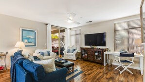 Un salon comprenant un canapé, des fauteuils, une table basse, un téléviseur et un ventilateur de plafond.
