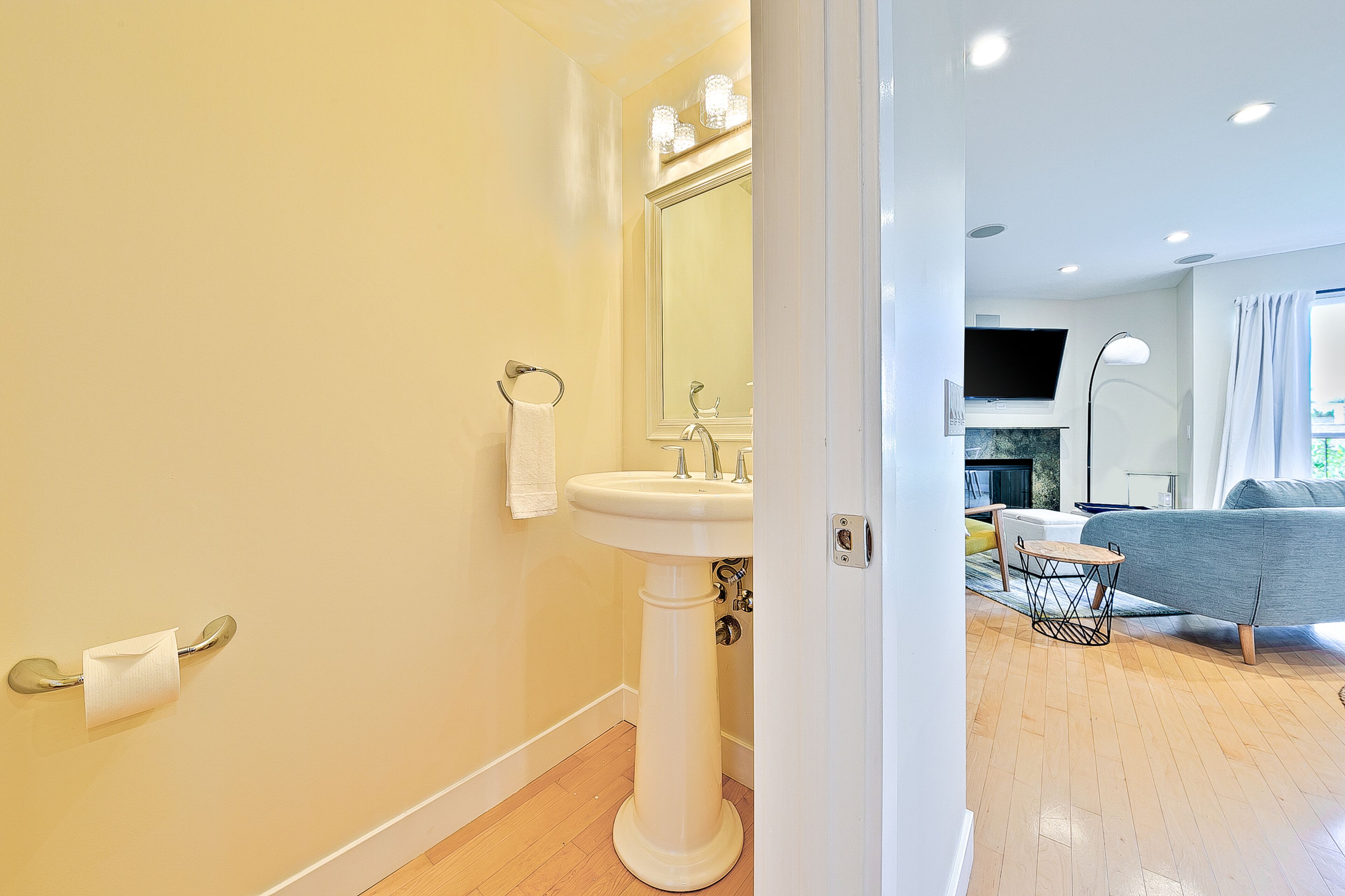 A bathroom with a pedestal sink, a towel rack, and a toilet paper holder.