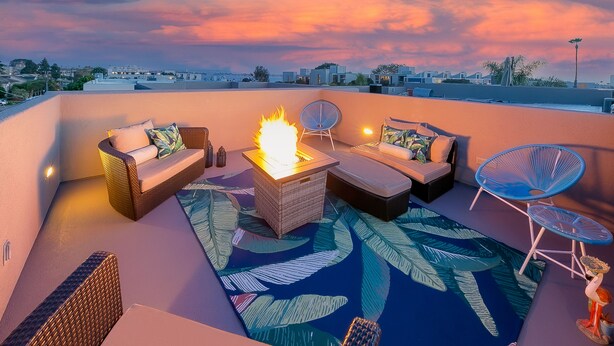 Terraza en la azotea con chimenea, asientos y vista del paisaje urbano al atardecer.