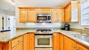 Una cocina con armarios de madera, estufa de acero inoxidable, microondas y encimera de granito.