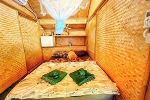 A narrow room with a bed, a small table, and a shelf with items. - khao Thung Benja HomeStay (Phayuha Khiri)
