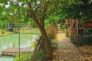 A tranquil garden with a water feature, wooden deck, and stone pathway. - khao Thung Benja HomeStay (Phayuha Khiri)
