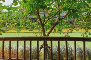 A view of a garden with a pond, a wooden fence, and a building in the background. - khao Thung Benja HomeStay (Phayuha Khiri)