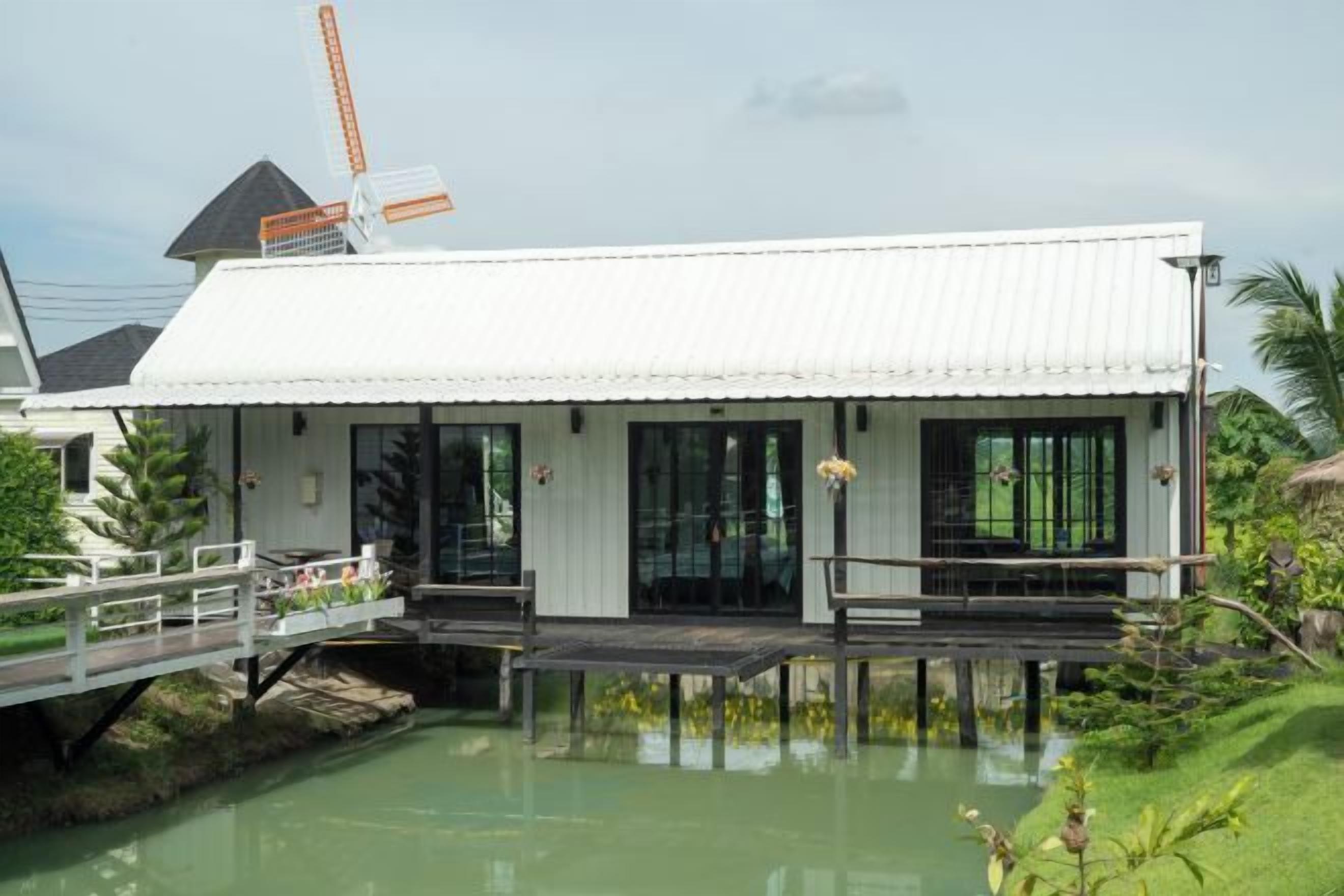 Un edificio blanco con un muelle que se adentra en el agua, rodeado de vegetación.